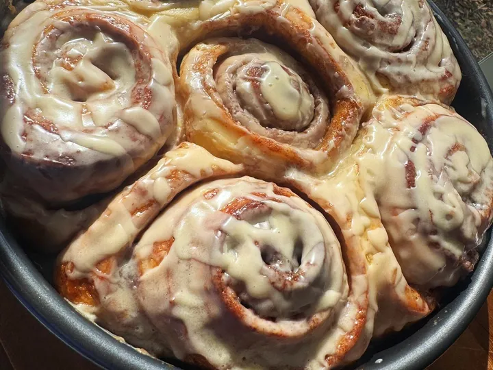 Round pan of cinnamon rolls topped with a thick vanilla glaze
