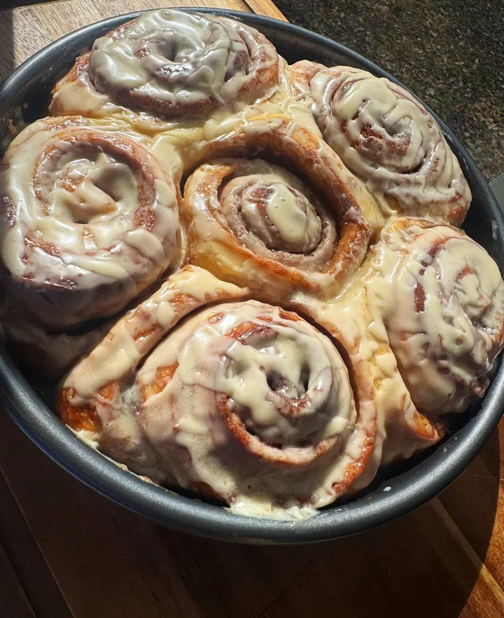 Round pan of cinnamon rolls topped with a thick vanilla glaze