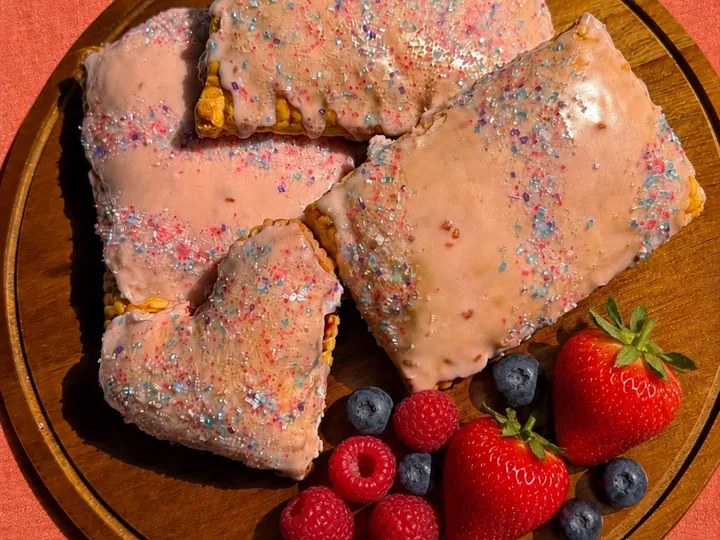 Sourdough mixed berry poptarts with pink icing and sprinkles beside fresh berries