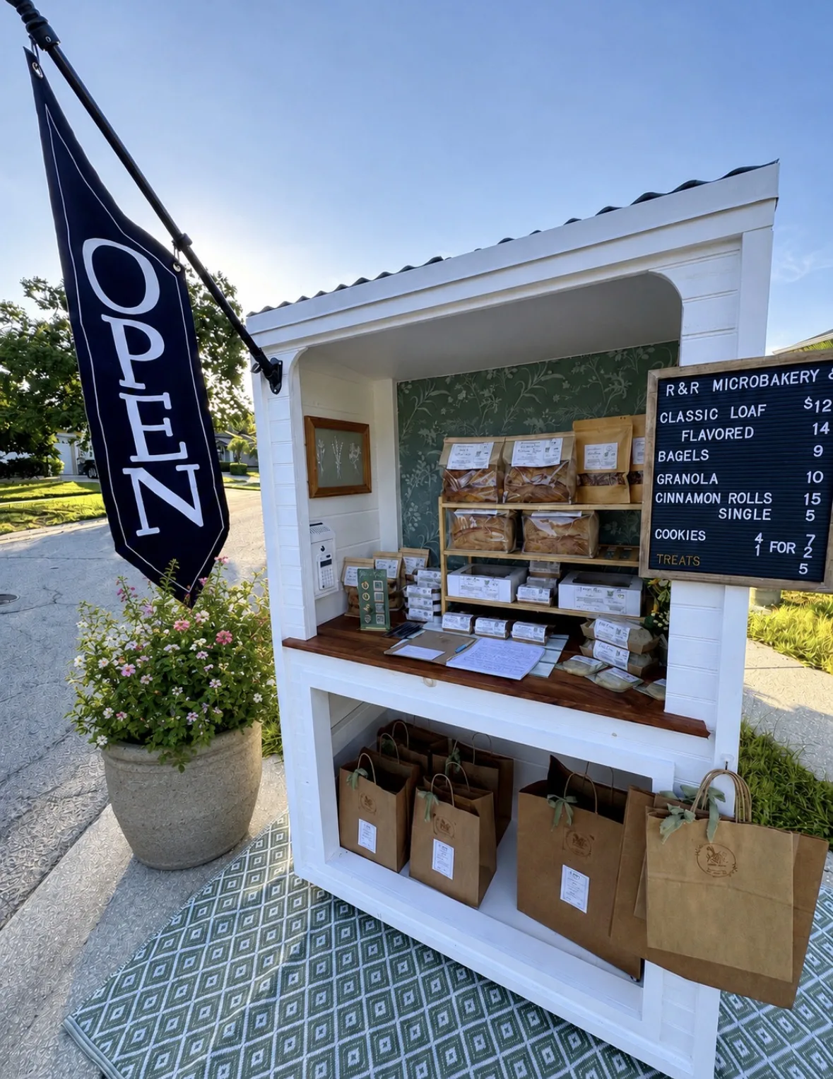 R&R Microbakery's stocked white self-serve bake stand with its open flag